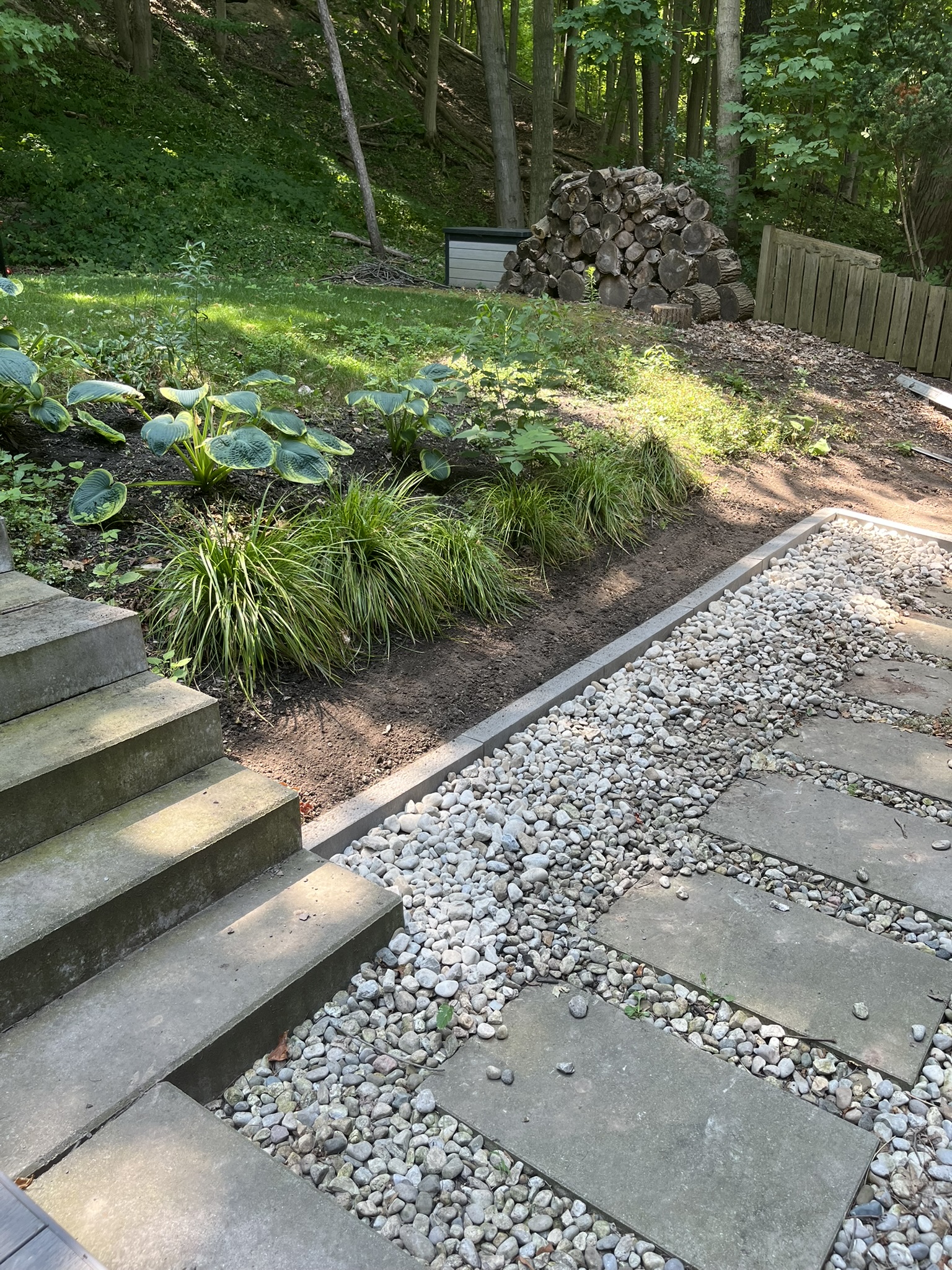 Natural stone steps and a river-rock path through a woodland garden
