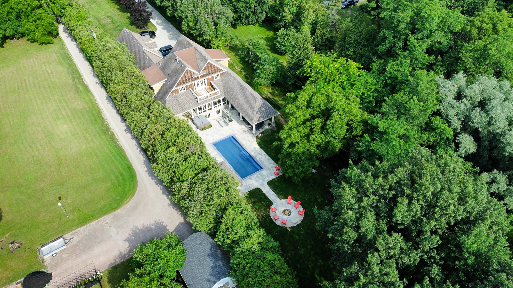 Aerial view of the estate showing the pool, flagstone deck, and fire-pit lounge beside the home