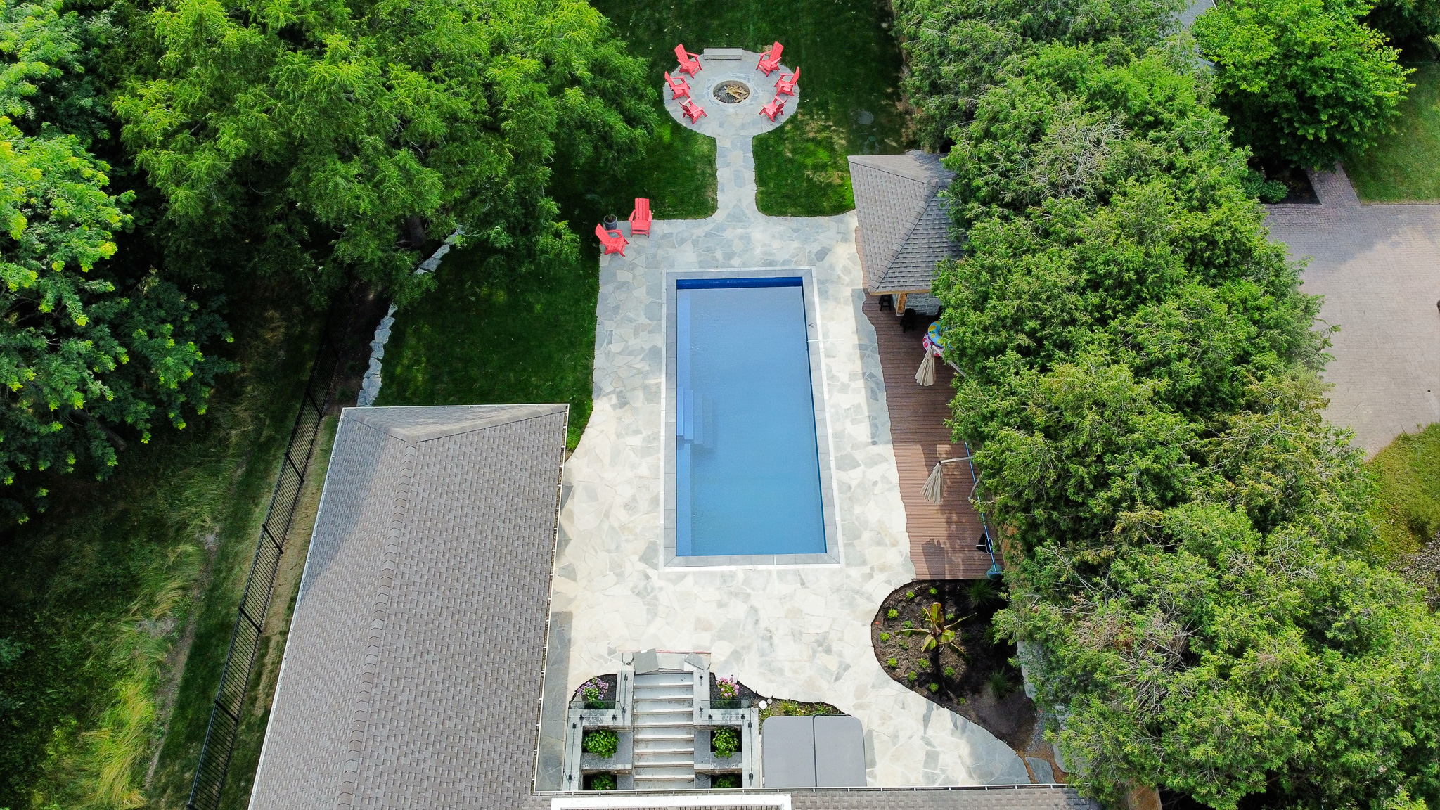 Overhead view of a rectangular pool framed by a stone deck and lounge area